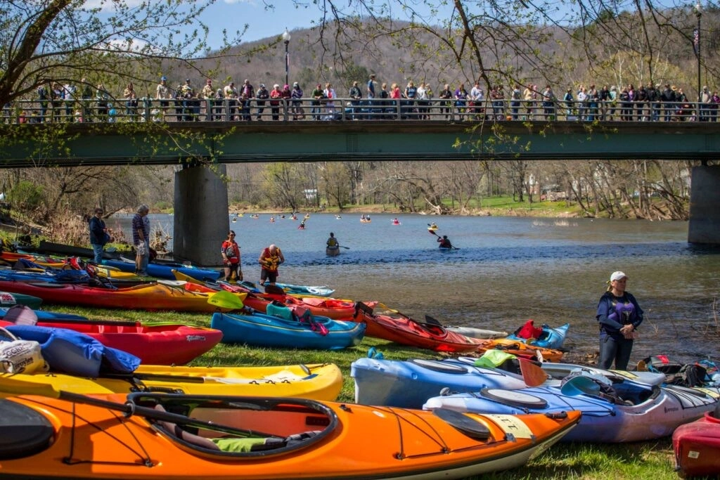 Kayaks of different shapes, sizes, and colors surrounding the Greenbrier River kayak launch