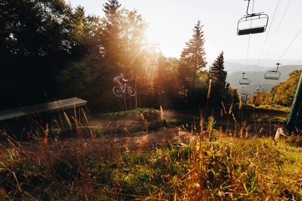Biker jumping down a ski slope with the ski lift in the background at Snowshoe Mountain, West Virginia.